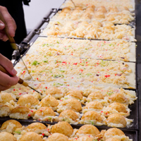 通販用冷凍たこ焼きを一つ一つ手焼きする様子